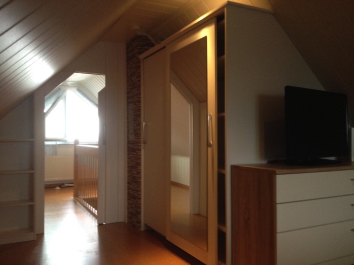 Innenansicht Einbauschrank Dachschräge mit Spiegel-Schiebetür und Regalen im Dachzimmer