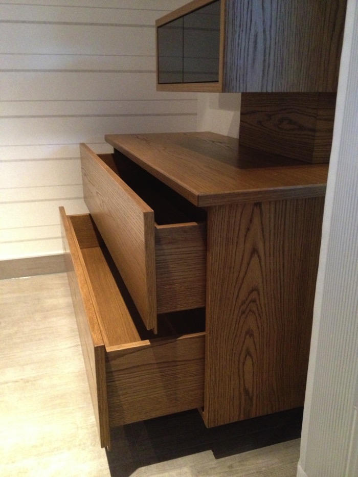 Detailaufnahme offener Schubkästen eines TV-Schrankes aus furnierter Eiche, grifflos auf Vollauszügen geführt