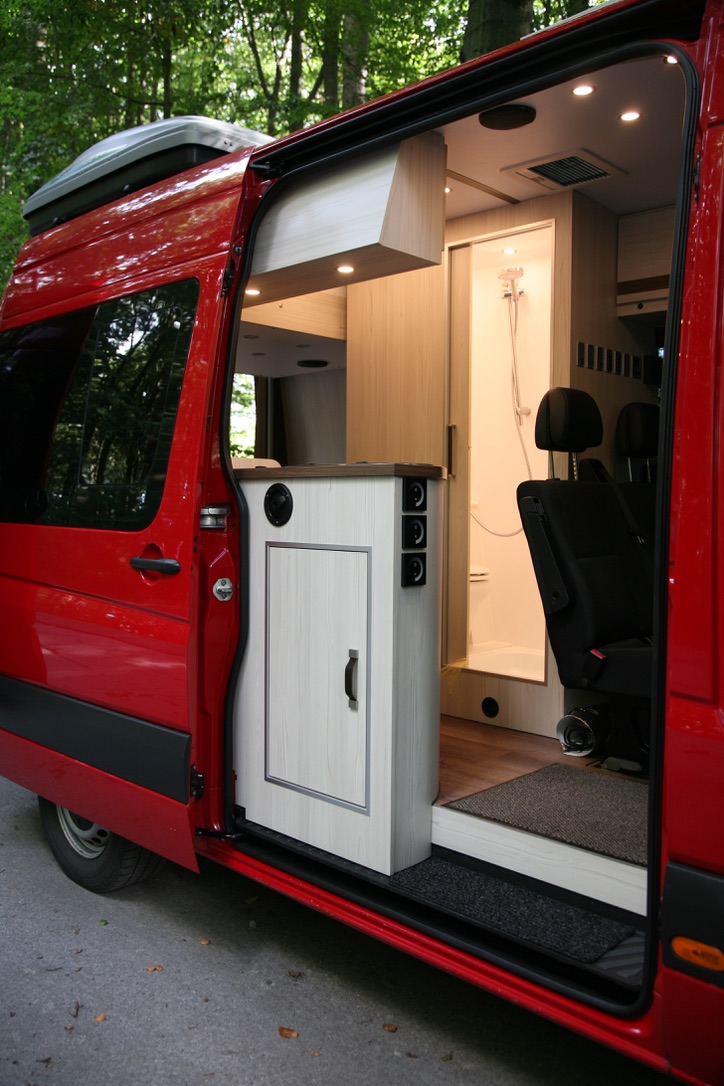 Sprinter Camperausbau – Blick durch die Seitentür auf vollwertige Dusche mit WC und Einbaumöbeln