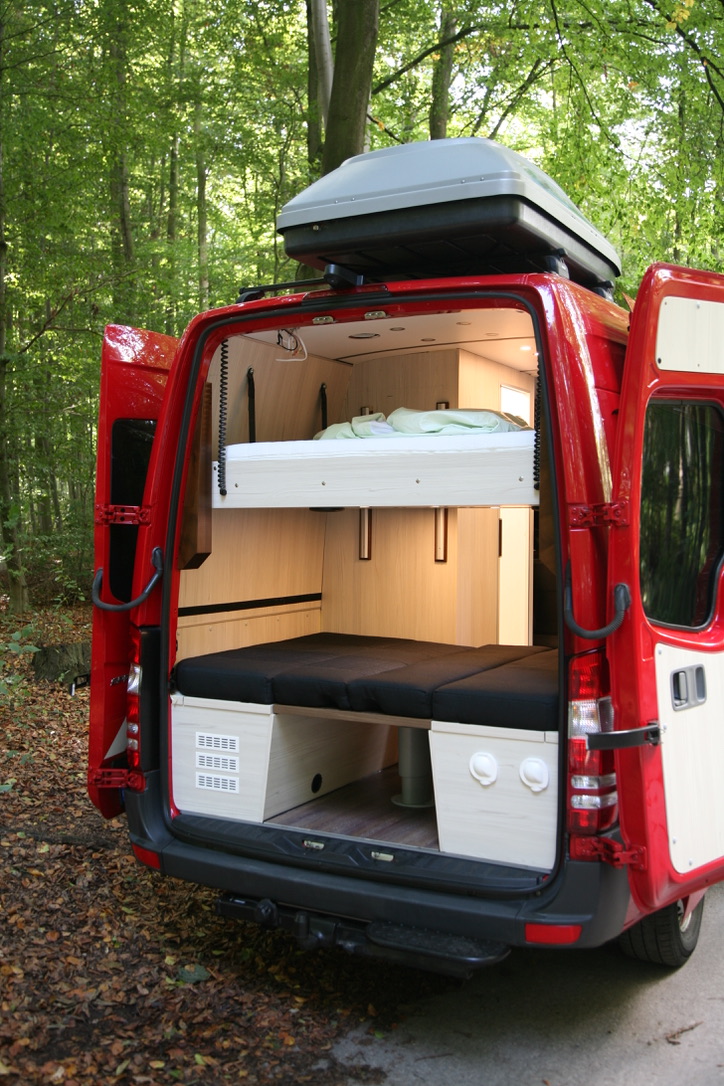 Sprinter Camperausbau – Blick durch die Hecktür auf abgesenktes Hubbett und unteren Schlafbereich