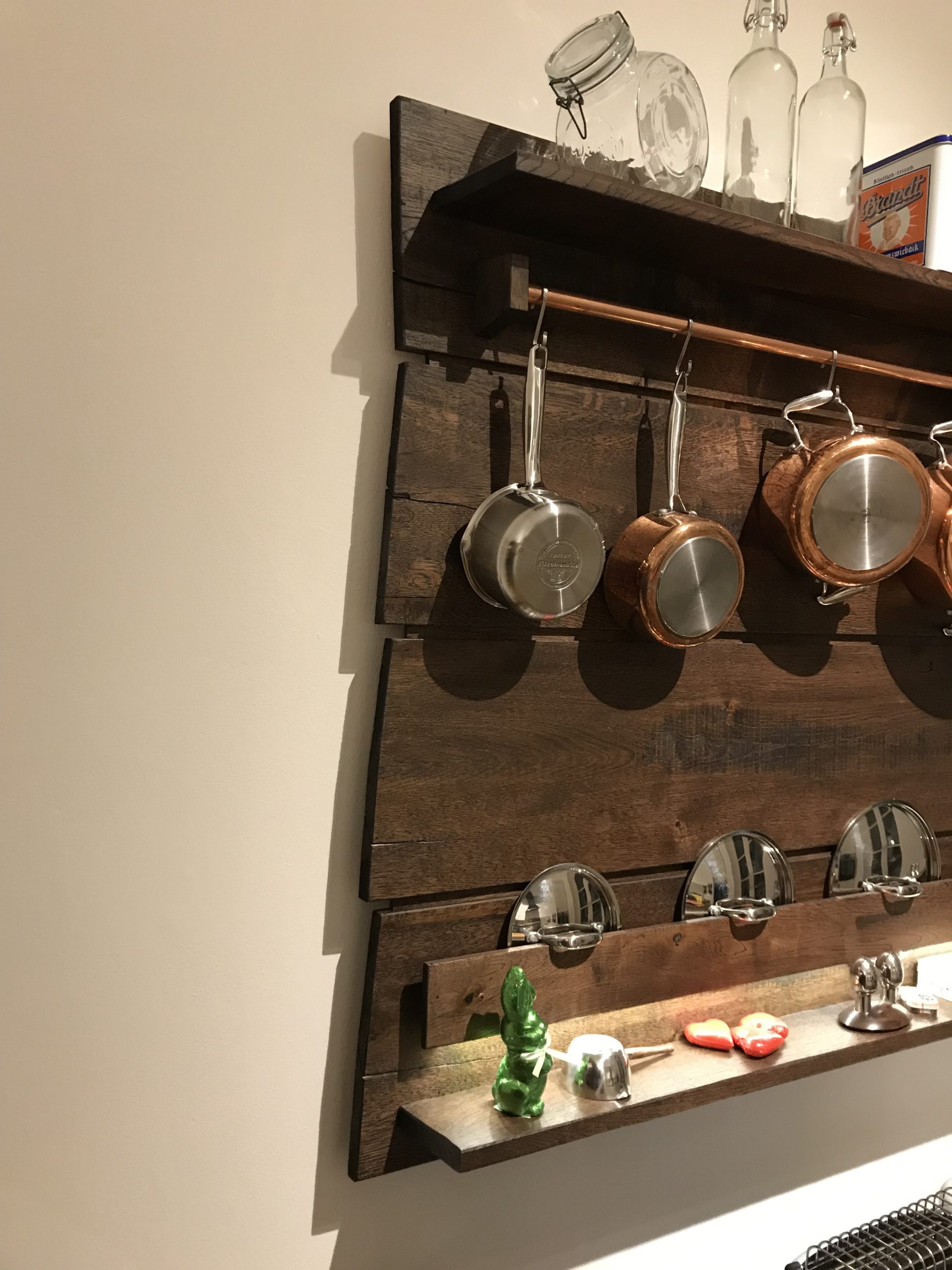 Detailansicht des Küchenregals aus Eiche: Kupferstange mit Pfannenhaltern und sägerauer Holzoberfläche