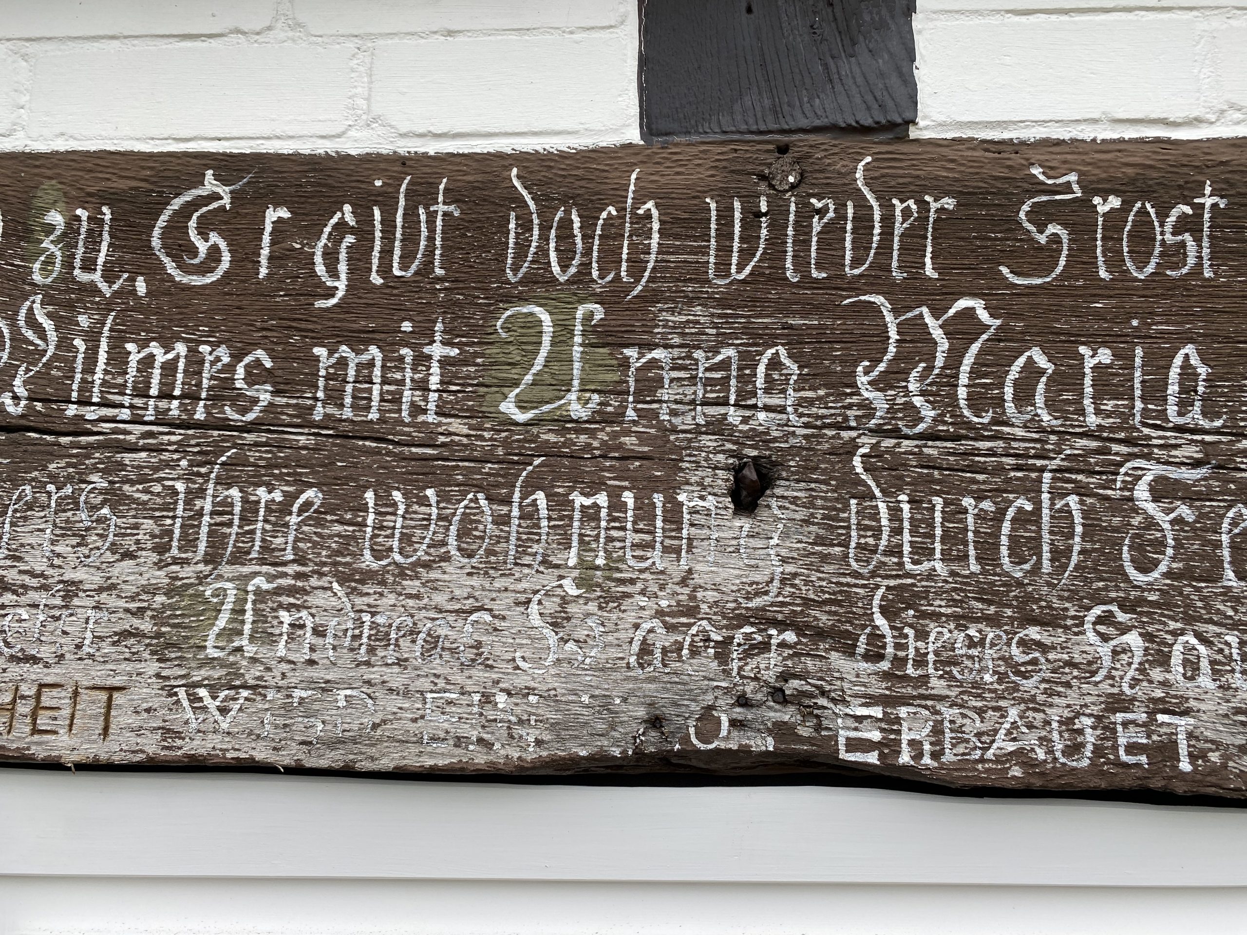 Schriftbalken restaurieren – verwitterter Inschriftbalken am Fachwerkhaus vor der Restaurierung
