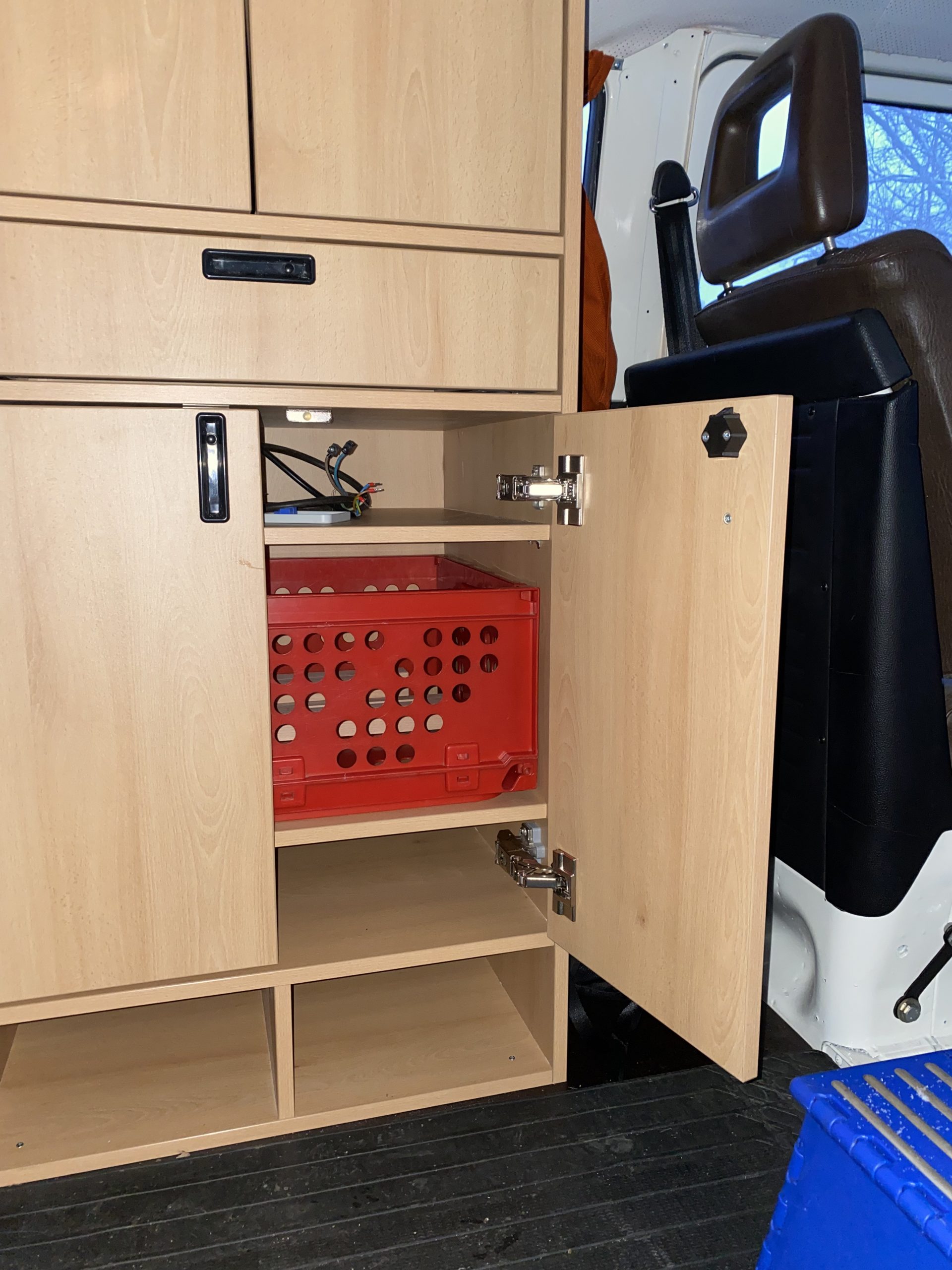 VW T2 Innenausbau – geöffneter Unterschrank mit passgenauem Stauraum für stapelbare Boxen und Elektroinstallation