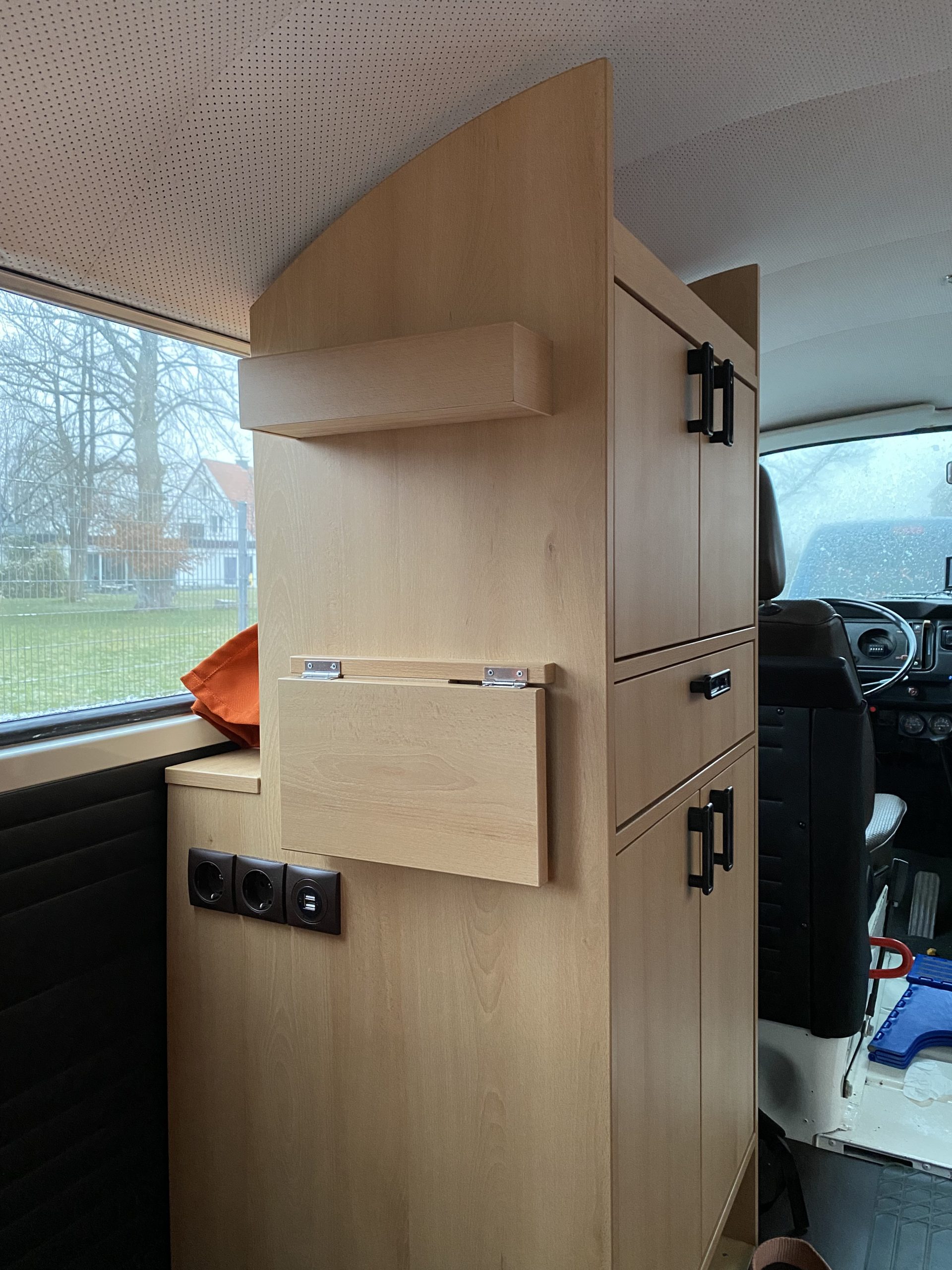 VW T2 Innenausbau – Stauraumschrank mit heruntergeklapptem Klapptisch und integrierten Steckdosen